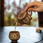 Amber tea gracefully pouring from the spout of the Cloud Thunder Yixing teapot into a matching white-slip painted teacup during a Gongfu tea session.
