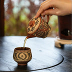 Amber tea gracefully pouring from the spout of the Ivory Canvas Yixing teapot into a matching white-slip painted teacup during a Gongfu tea session.