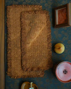An overhead view of a traditional tea table setting featuring two layered persimmon-dyed tea mats, with the small mat resting elegantly on top of the medium mat, ready for a tea ritual.