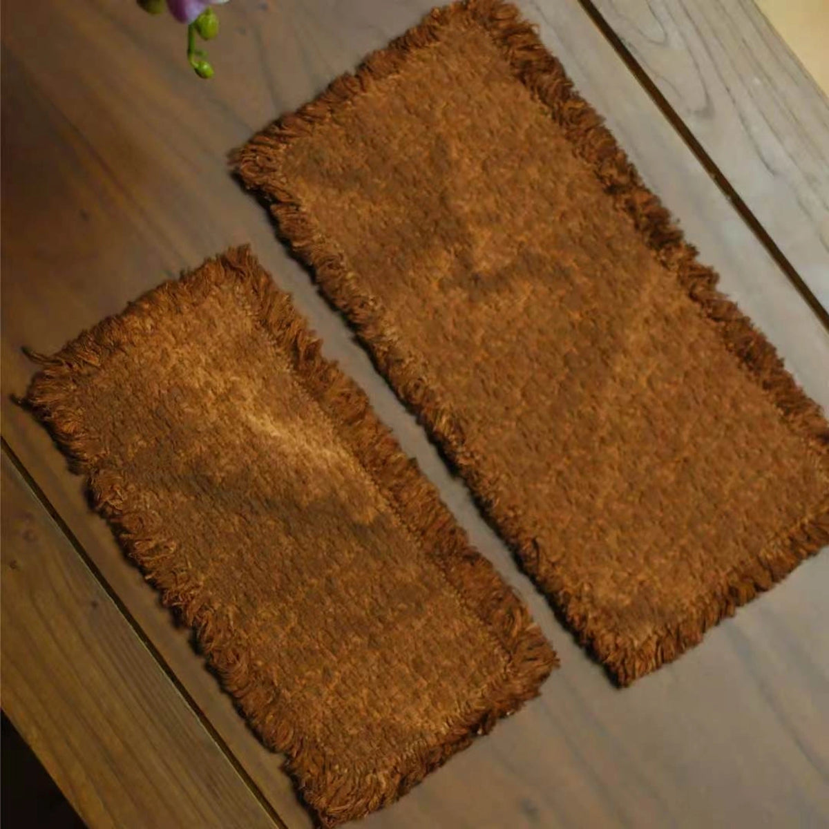 A side-by-side size comparison of the small and medium handcrafted persimmon-dyed tea mats, viewed from above to highlight their natural dye variations and dimensions.