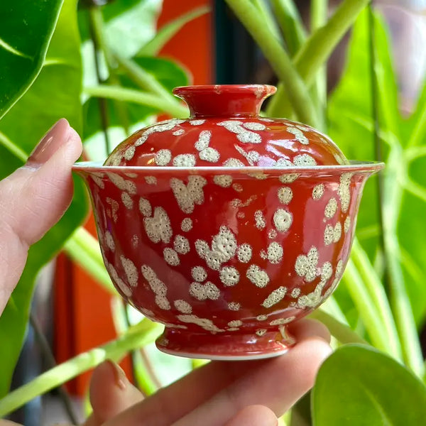 A hand holding the 50ml Phoenix Spark Solo Gaiwan to demonstrate its small, ergonomic scale. The image illustrates how the petite vessel fits perfectly in the palm for a comfortable and intimate solo tea ritual.
