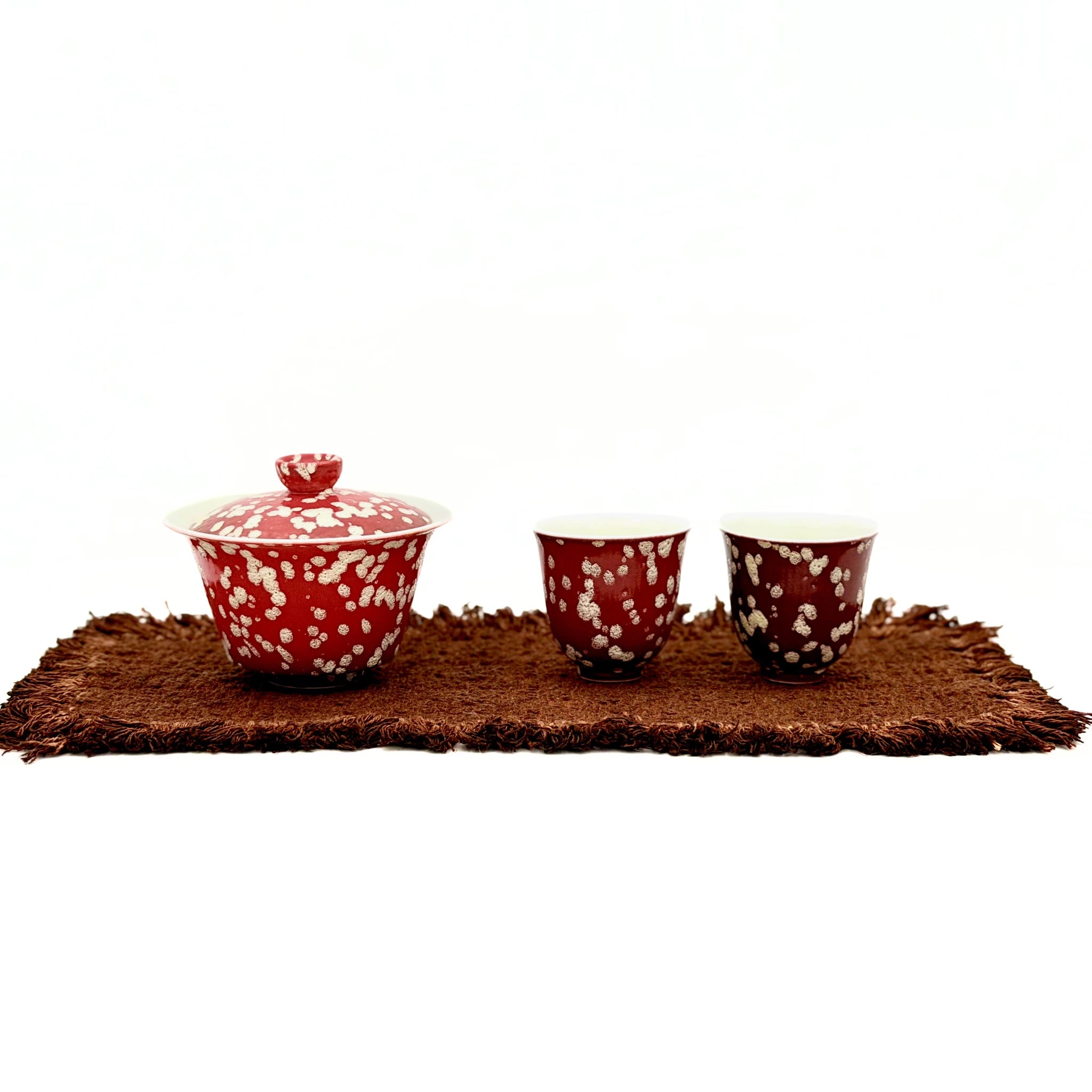 A professional studio photograph of the complete Phoenix Spark Chinese Wedding Tea Set, showing the gaiwan and two tasting teacups arranged on a traditional tea mat against a white background.