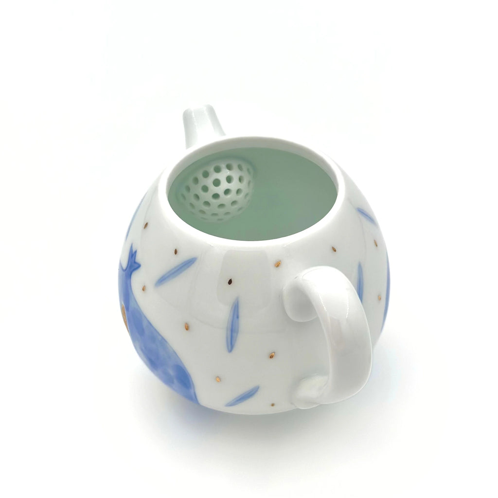 White ceramic tea infuser with blue floral patterns on a white background