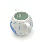White ceramic tea infuser with blue floral patterns on a white background