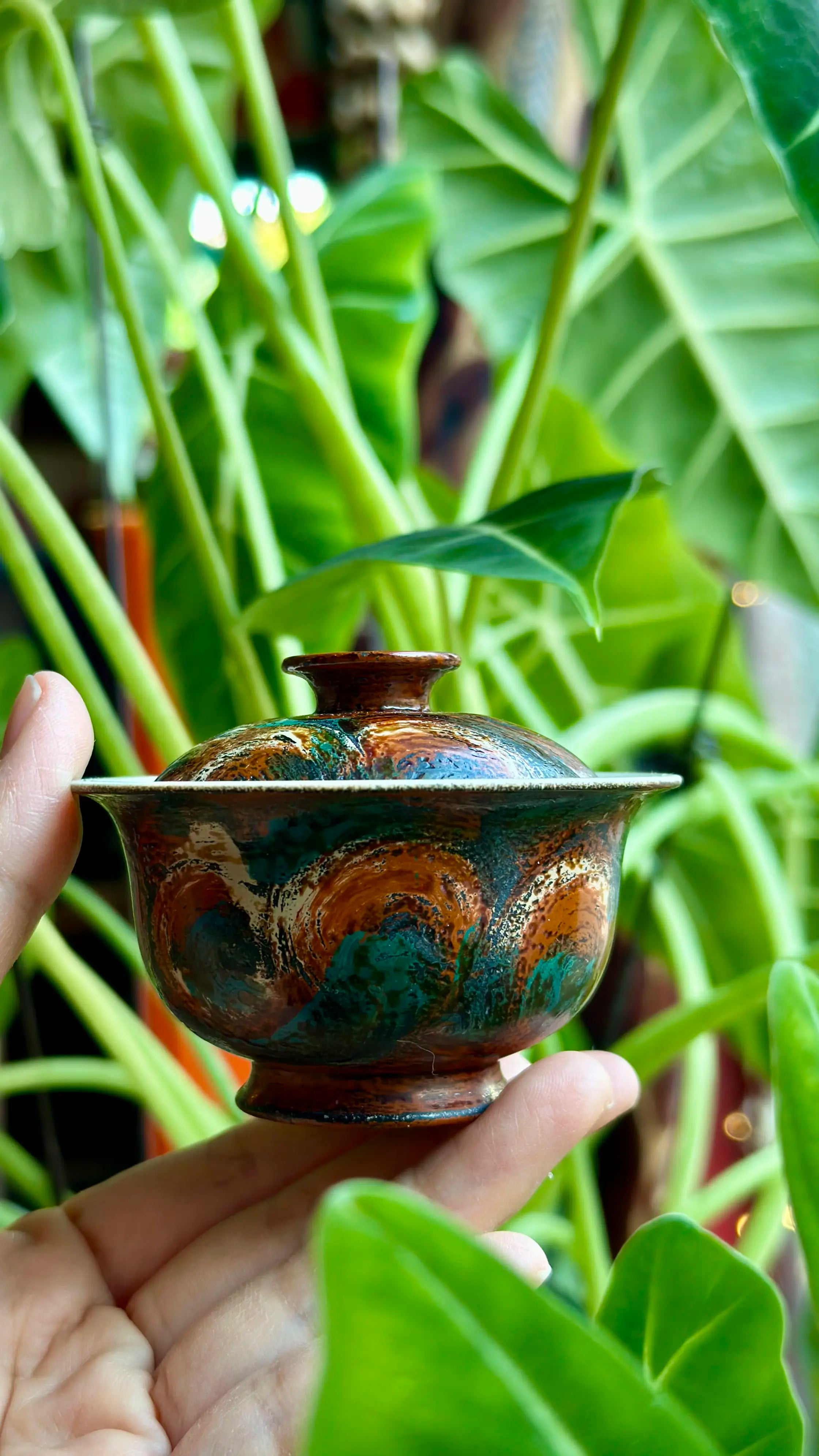 Lifestyle shot of the Vintage Flora 60ml gaiwan held against a natural green plant background.