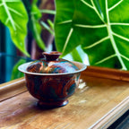 Urushi gaiwan with on a bamboo tray with green leaves in the background