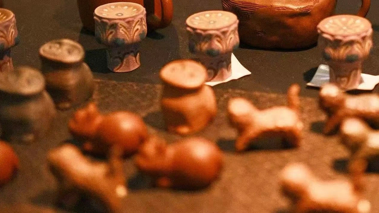 Collection of small ceramic figurines teapets on a dark tea mat